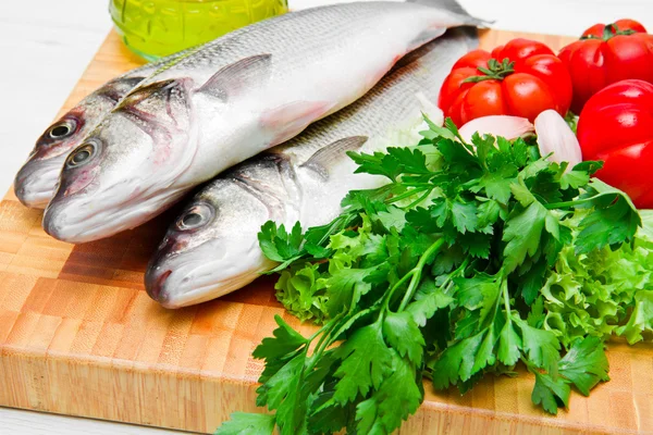 Paar frischer Seebarsch mit Gemüse auf Holz — Stockfoto