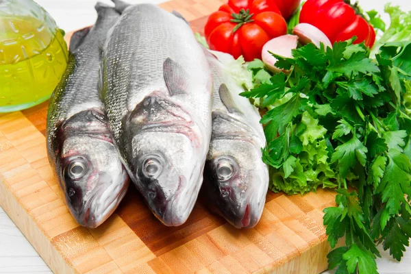 Par färska havsabborre med grönsaker på trä — Stockfoto