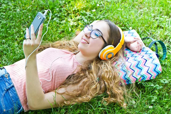 Krásná dívka relaxační a poslouchejte hudbu ve sluchátkách v th — Stock fotografie