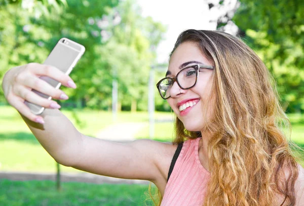 Портрет красивой девушки, делающей селфи с помощью мобильного телефона — стоковое фото