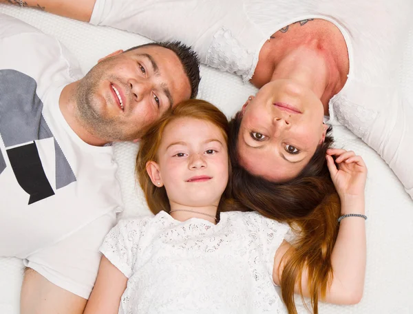 Famille souriante s'amuser allongé sur le lit — Photo