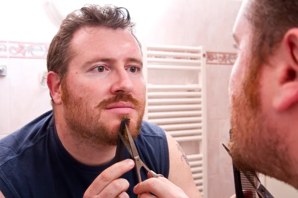 Hombre limpiando su barba con tijeras — Foto de Stock