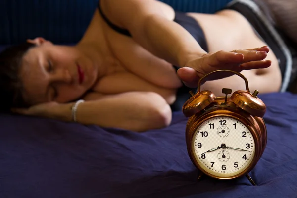 Güzel genç kadın çalar saat ile uyanma — Stok fotoğraf