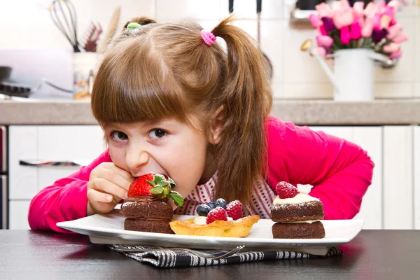 Bambina che prepara e mangia torta con frutta — Foto Stock