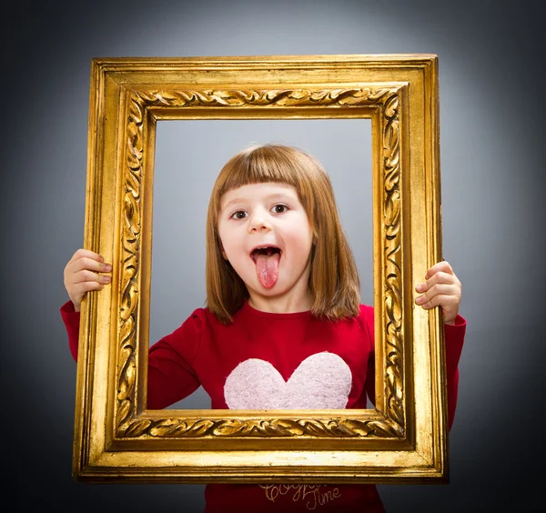 Smiling girl looking through a vintage picture frame — Stock Photo, Image