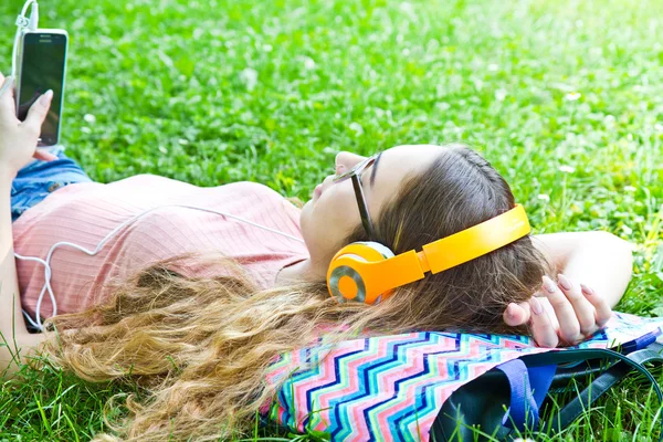 Krásná dívka relaxační a poslouchejte hudbu ve sluchátkách v th — Stock fotografie