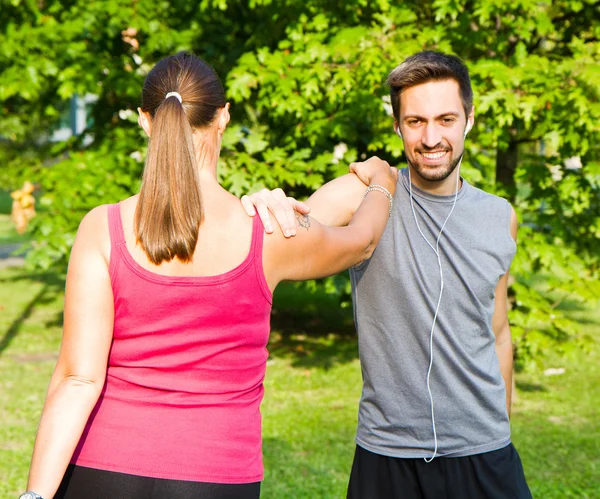 Leende par gör streching i parken — Stockfoto