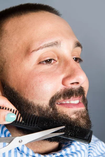 Mulher está aparando a barba de um jovem — Fotografia de Stock