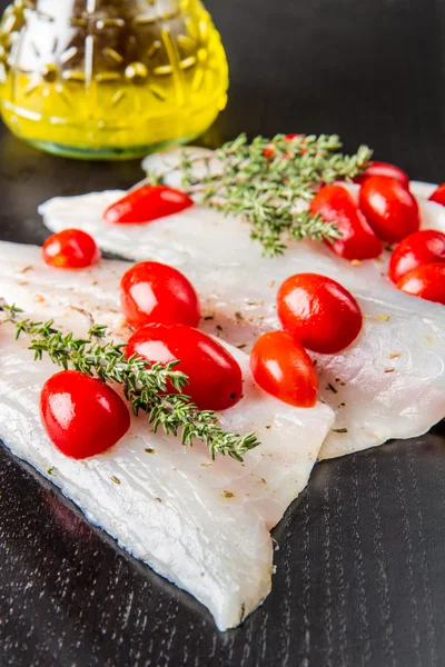 Filetes de robalo cru com tomates cereja em madeira preta — Fotografia de Stock