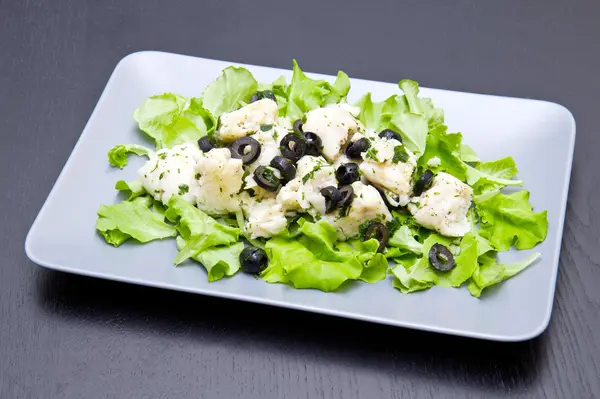 Schotel van kabeljauw salade met zwarte olijven — Stockfoto