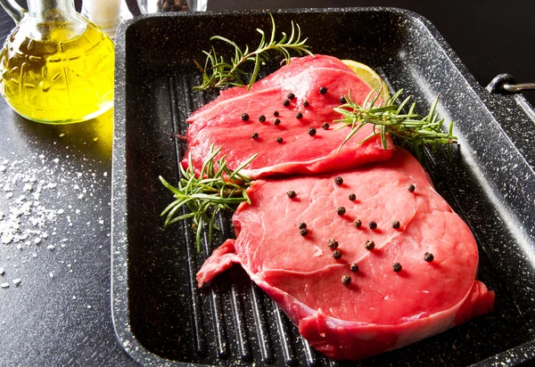 Carne crua em fatias no pote da placa no fundo preto — Fotografia de Stock