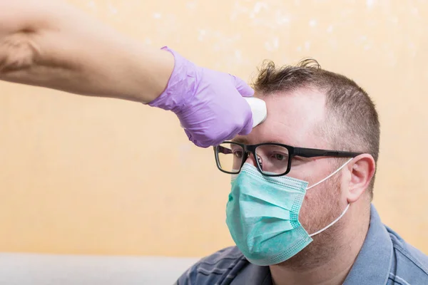 Coronavirus Krankenschwester Trägt Handschuhe Und Hält Medizinisches Infrarot Stirnthermometer Die lizenzfreie Stockfotos