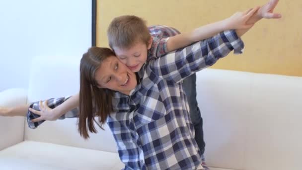 Щаслива Молода Мама Піднімає Милий Маленький Син Граючи Літаку Дивані — стокове відео