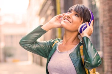 Genç kız kulaklığı elleriyle tutarak müzik dinliyor. Boş zamanlarında rahatlama ve eğlence kavramı