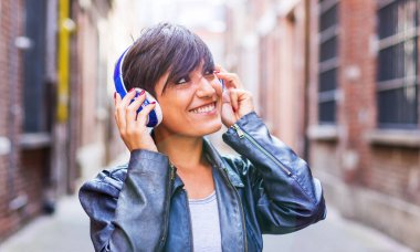 Genç kız kulaklığı elleriyle tutarak müzik dinliyor. Boş zamanlarında rahatlama ve eğlence kavramı