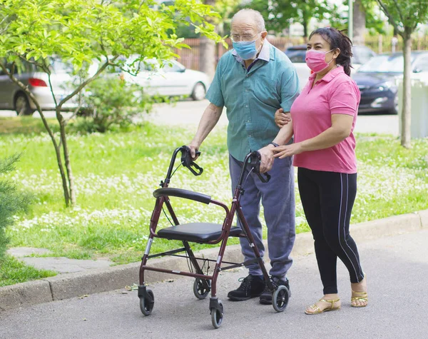 Joven Cuidador Acompaña Anciano Caballero Ayudándole Caminar Parque — Foto de Stock