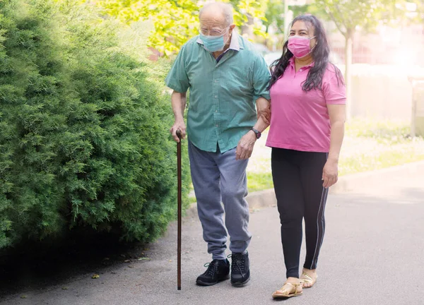 若い介護者が老人を連れて公園を歩くのを手伝ってくれます — ストック写真