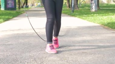 Kız parkta ip atlayıp zıplıyor.