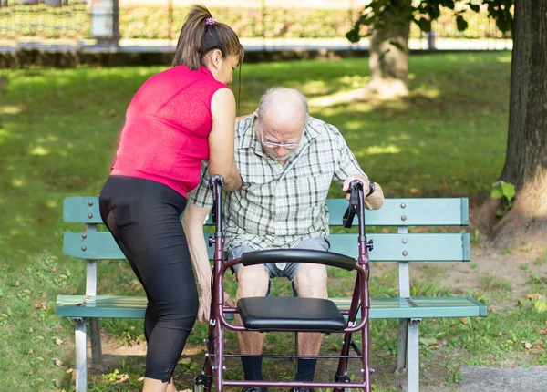 Cuidador Español Está Ayudando Sentarse Banco Parque Hombre Mayor —  Fotos de Stock