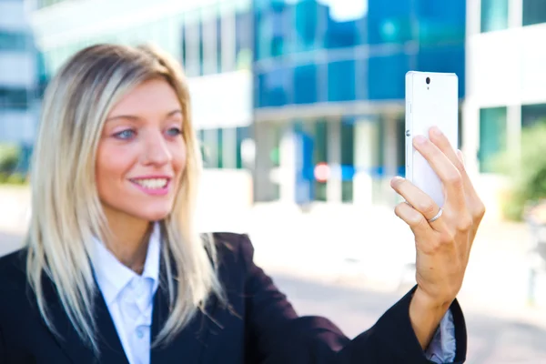 Beautiful business woman takes a selfie with her cell phone — Stock Photo, Image