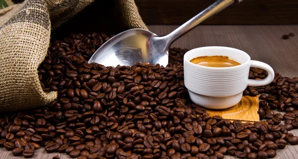 Kaffeetasse mit gerösteten Bohnen auf rustikalem Tisch — Stockfoto