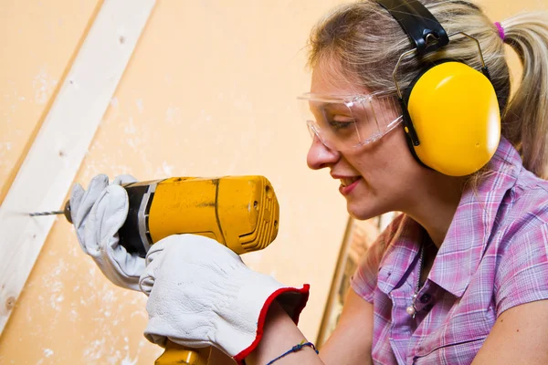 Carpinteiro feminino no trabalho usando máquina de perfuração de mão — Fotografia de Stock