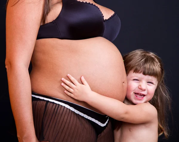 Happy kid girl hugging pregnant mother's belly — Stock Photo, Image