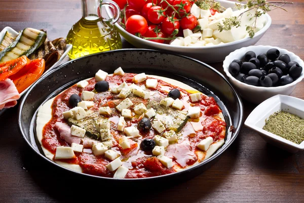Pizza med skinka, paprika, zucchini och svarta oliver ingredienser — Stockfoto