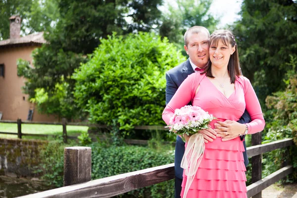 Foto van de bruid en bruidegom op een brug in de buurt van een park — Stockfoto