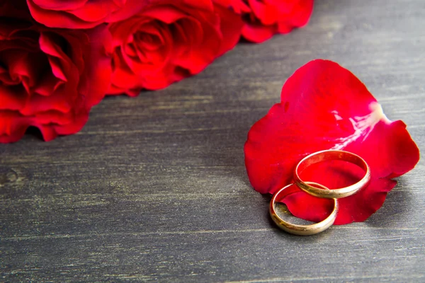 Dia dos namorados Rosas vermelhas e anel de casamento um fundo de madeira — Fotografia de Stock