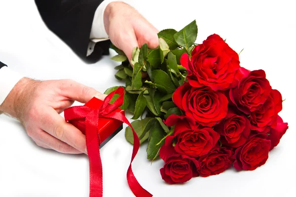 Mano dell'uomo con bouquet di rose rosse e confezione regalo — Foto Stock