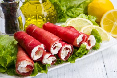 Beyaz tabakta kurutulmuş et ve peynir. 