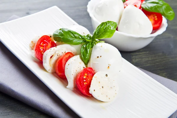 Tomaten und Mozzarella mit Basilikumblättern — Stockfoto