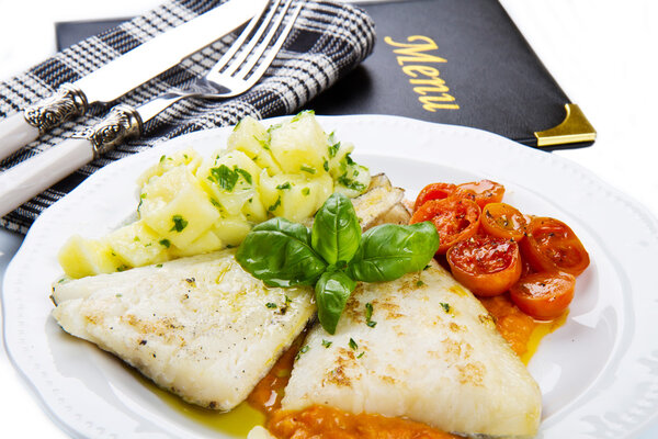 white dish of Fresh black cod with potatoes and tomatoes sauce