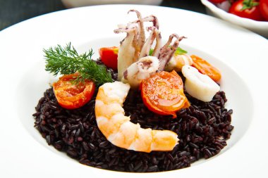 Dilimlenmiş mürekkep balığı, karides ve domatesli siyah pirinç.