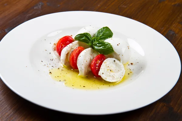 Tomaat en mozzarella met basilicum bladeren op een plaat — Stockfoto