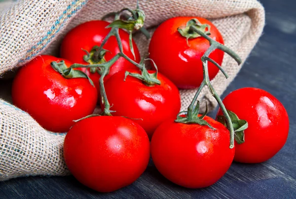 Tomates frescos en saco de arpillera sobre madera —  Fotos de Stock