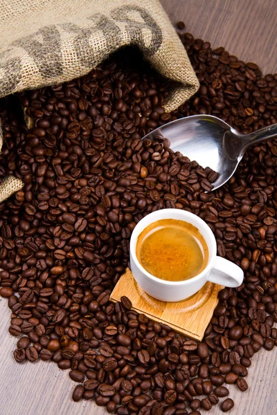 Koffiekopje met jute zak van geroosterde bonen — Stockfoto