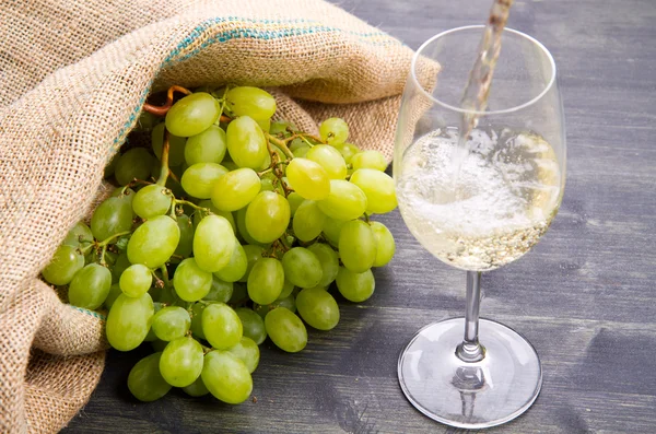 Куча зеленого винограда и вина на деревянном фоне — стоковое фото