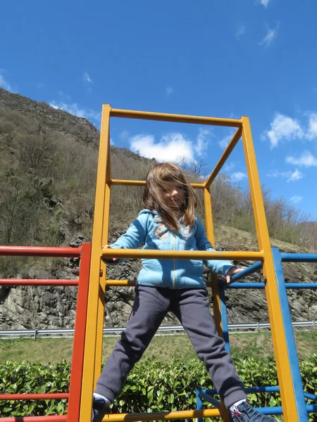 Linda niña está escalando en el equipo del parque infantil —  Fotos de Stock