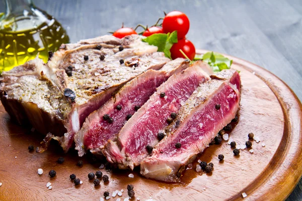 Filé de carne fatiada grelhada no fundo de madeira — Fotografia de Stock