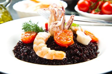 Dilimlenmiş mürekkep balığı, karides ve domatesli siyah pirinç.