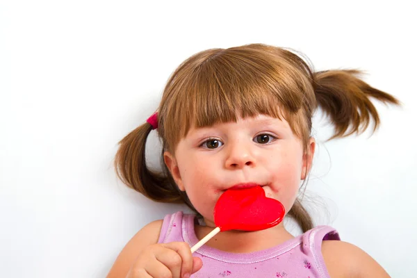 붉은 마음 사탕을 먹는 어린 소녀 — 스톡 사진