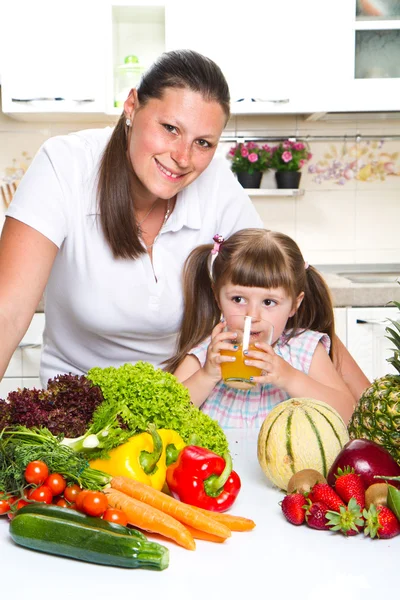 Schöne junge Frau gibt dem kleinen Mädchen Orangensaft in — Stockfoto