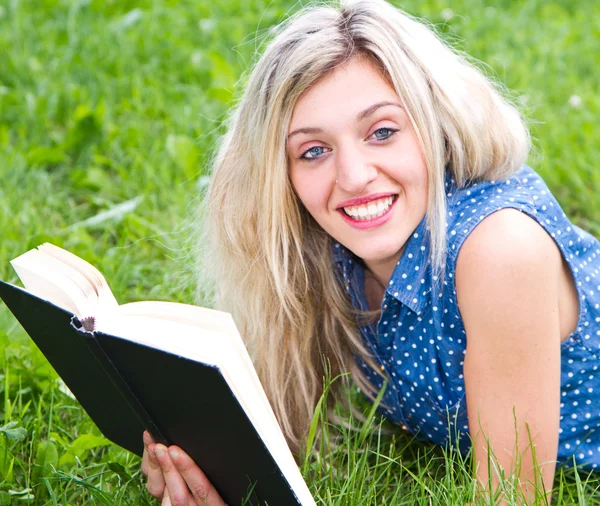 美しい少女は草原に位置し、本を読みます — ストック写真