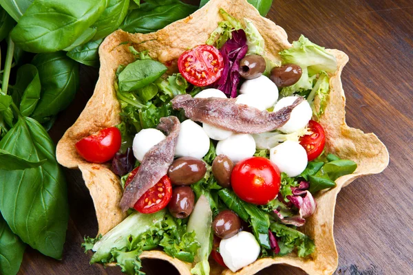 Salada mista com mussarela e anchova em uma cesta de pão — Fotografia de Stock