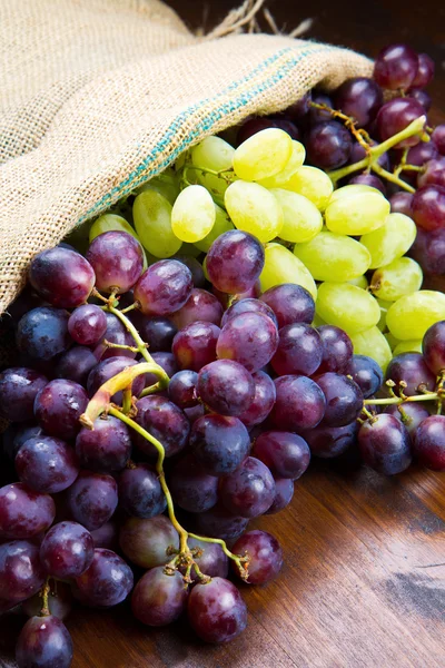 Cachos de uvas pretas e verdes em fundo de madeira — Fotografia de Stock