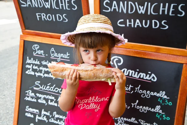 Νεαρό κορίτσι τρώει ένα μεγάλο σάντουιτς — Φωτογραφία Αρχείου