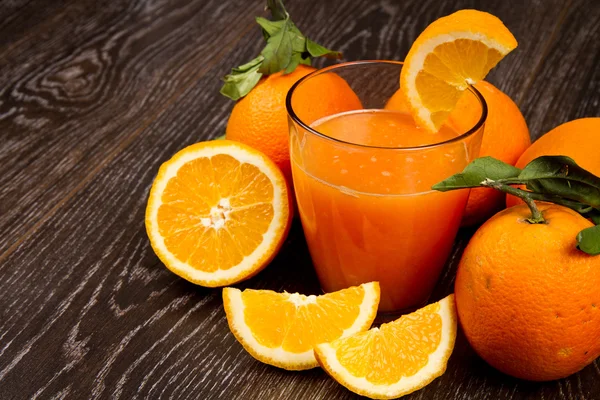Verre de jus d'orange frais et d'oranges sur fond en bois — Photo