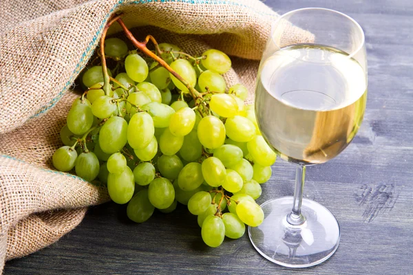 Cachos de uvas verdes e vinho em fundo de madeira — Fotografia de Stock